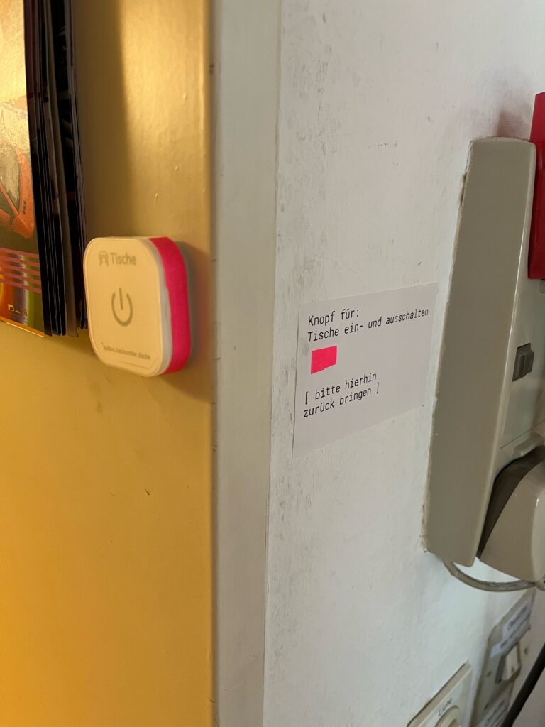 Eine Nahaufnahme vom Schalter am Türrahmen und der Beschriftung daran. Der Schalter und die Beschriftung sind pink hervorgehoben.