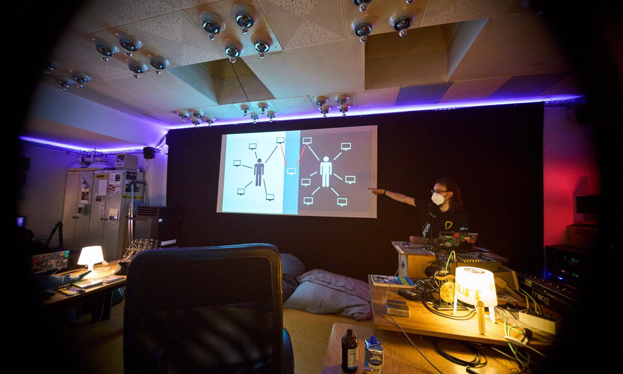 ein Vortrag am Freitagabend: auf der Leinwand ist eine Folie sichtbar, am Pult steht jemand und zeigt drauf