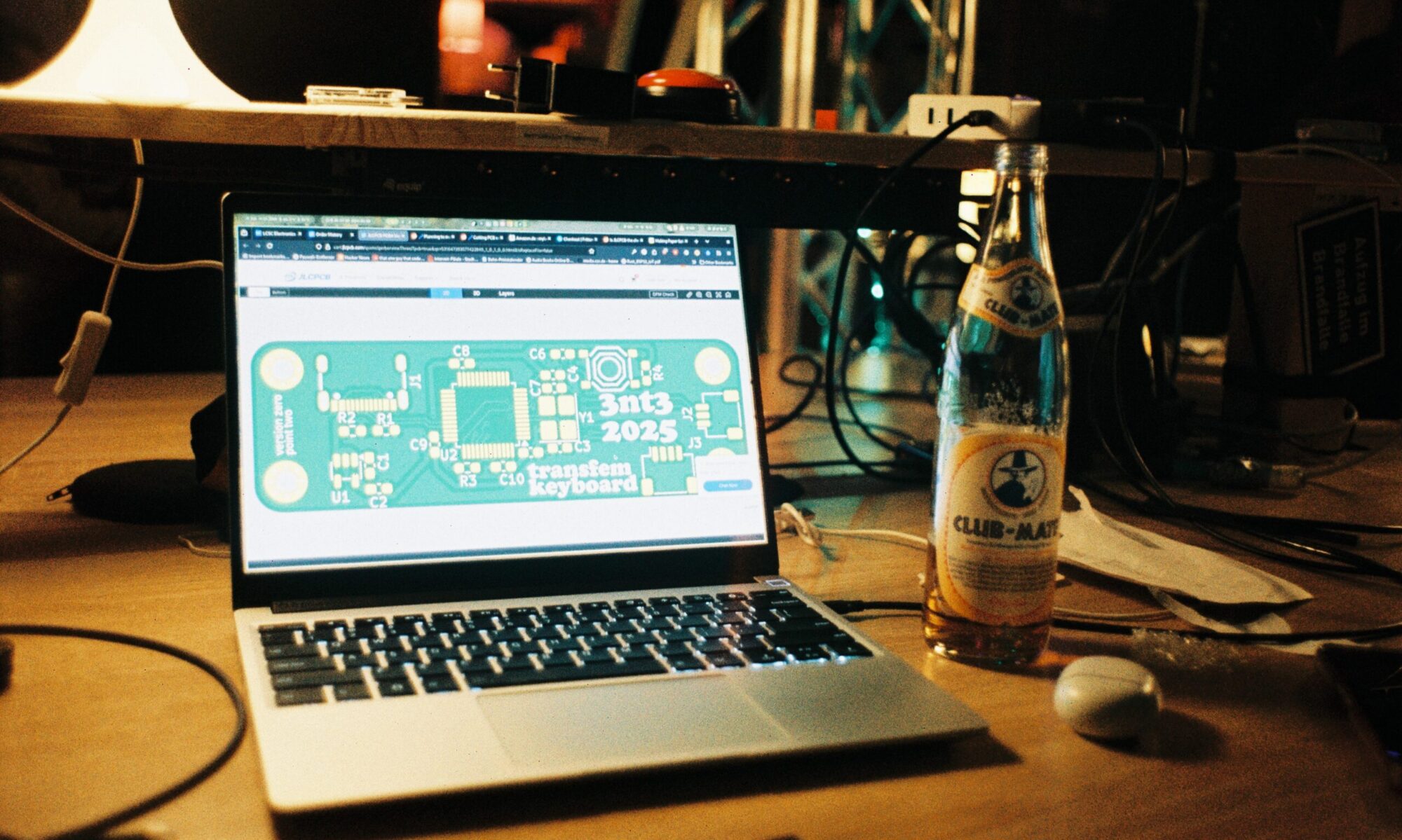 laptop showing a pcb design, club-mate bottle standing to the right of it